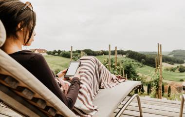 Frau liest auf eigener Terrasse im Weingarten-Resort Unterlamm Loipersdorf
