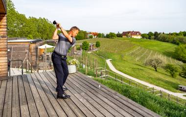 Mann übt seinen Abschlag im Golf auf einem Holzplateau in den Weinreben