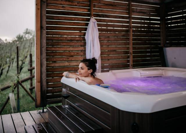 Frau im Outdoor Whirlpool mit Glas Rotwein