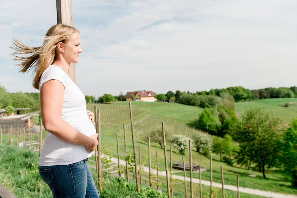 Schwangere Frau auf Terrasse mit Blick auf Weinberge